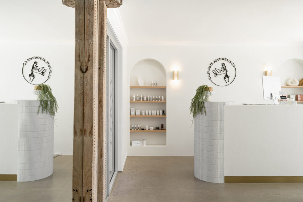 Custom joinery with brass features, hardwood floors and welcoming reception area for this wellness & beauty fit out for Illuminate Aesthetics